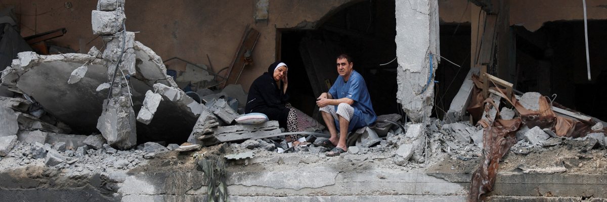 Palestinci sedí mezi troskami poškozené budovy po izraelských úderech ve městě Gaza