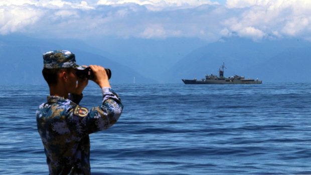 Čínský voják sleduje tchajwanskou fregatu