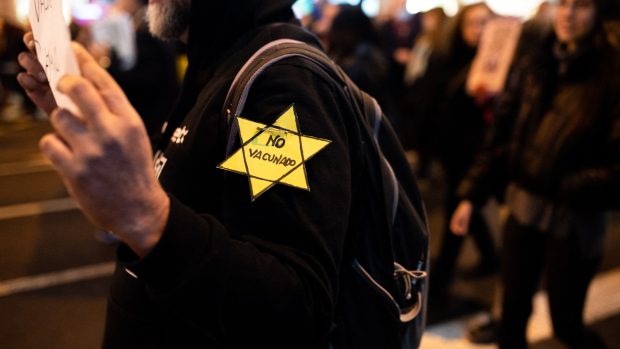 Muž se židovskou hvězdou a nápisem Neočkován na protestech v Barceloně