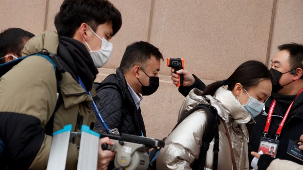 Novináři v Pekingu procházejí před vstupem na tiskovou konferenci kontrolou, během které jim je měřena teplota. Jedním z příznaků nemoci, kterou způsobuje nový koronavirus, je totiž zvýšená teplota.