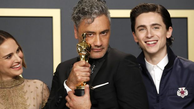 Uprostřed Taika Waititi s Oscarem za nejlepší scénář za snímek Králíček Jojo. Vedle něj herci Natalie Portmanová a Timothée Chalamet, kteří mu sošku předávali.
