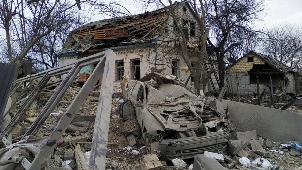 Zničené auto a zničený dům po ostřelování v obci Marhalivka v Kyjevské oblasti