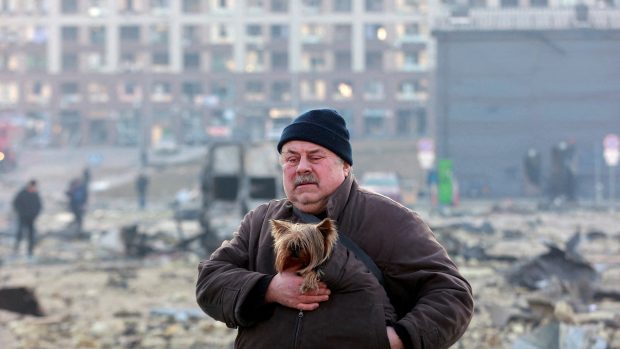 Muž se psem na místě bombardováním poničeného nákupního centra v Kyjevě