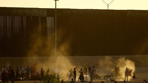 Migranti se shromažďují u hraniční zdi po překročení řeky Rio Bravo s úmyslem přihlásit se agentům americké pohraniční stráže a požádat o azyl, pohled z Ciudad Juarez