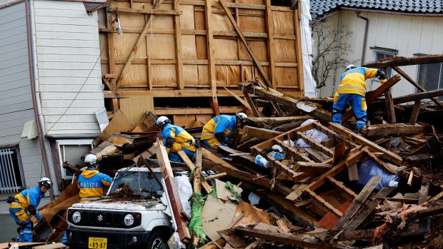 Příslušníci polici pracující v troskách spadlého domu po zemětřesení ve městě Wadžima