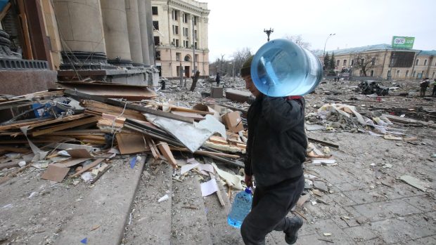 Muž nese barely s vodou do budovy charkovské oblastní správy. V pozadí je možné vidět následky ostřelování centra Charkova ruskou armádou
