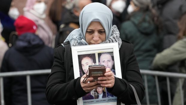 Žena stojí před budovou soudu v německém Koblenzu a drží fotografie svých pěti bratrů, kteří zemřeli v Sýrii