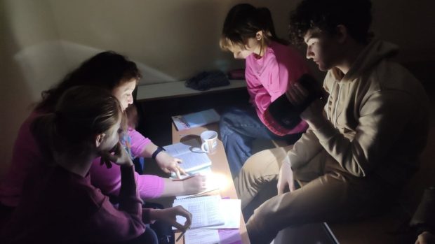 Děti se učí v protiraketovém krytu. Na učebnice si svítí baterkou.