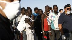 Policie doprovází migranty, kteří vystoupili z lodi námořnictva v sicilském přístavu Pozzallo