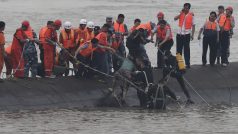 Záchranáři pomáhají pasažérům, kteří byli uvezněni v trupu lodi. Mnoho lidí je stále nezvěstných