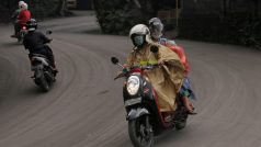Lidé na Bali jedou na skútrech po cestě pokryté popelem ze sopky Agung