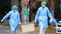 Dvojice zdravotníků odnáší kontaminovaný materiál z nemocnice ve Wu-chanu, kde jsou hospitalizováni pacienti s novým koronavirem