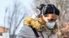 Žena s obličejovou maskou opuští nemocnici v italském městě Codogne.