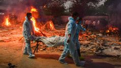 Pracovníci v Indii připravují tělo člověka, který zemřel kvůli coronaviru, ke kremaci.