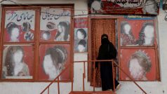 Žena v nikábu vstupuje do kosmetického salonu v Kábulu s poničenou reklamou.