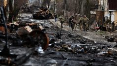 Vojáci prochází kolem zničené ruské techniky ve městě Buča nedaleko Kyjeva