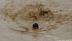 Muž plave v záplavové vodě, během monzunového období v Čarsadě