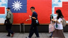 Lidé v Tchaj-peji procházejí kolem tchajwanské vlajky