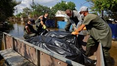 Dobrovolníci nakládají pytle s těly vytaženými ze zatopených domů po zničení Kachovské přehrady