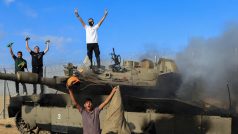 Palestinci oslavují hořící izraelské vojenské vozidlo zasažené palestinskými ozbrojenci, kteří pronikli do oblastí jižního Izraele