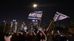 Lidé s izraelskými vlajkami vítají ve městě Petach Tikva vrtulník s propuštěnými rukojmími