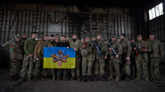 Bachmutští vojáci a Volodymyr Zelenskyj s vlajkou Ukrajiny se znakem dělostřeleckého pluku