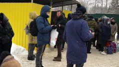 Před nízkým žlutým domkem přešlapují ve sněhu desítky lidí s igelitovými taškami popsaných jmény jejich blízkých.