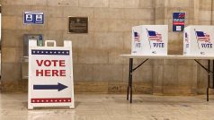 Manažeři voleb nasměrují voliče do jedné z hlasovacích budek, kde si mohou v soukromí lístky upravit