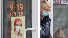 Obyvatelka Simferopolu vychází ze dveří s letákem vyzývající ke vstupu jen s rouškou