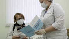 Pacientka moskevské nemocnice si prohlíží certifikát o očkování, který získala po obdržení vakcíny proti koronaviru
