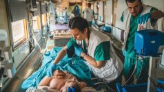 Zdravotnický tým se snaží stabilizovat vážně zraněného pacienta uvnitř evakuačního vlaku