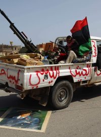 Vozidlo povstalců přejíždí portrét Muammara Kaddáfího.