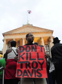 Demonstrant drží plakát s nápisem: „Nezabíjejte Troye Davise.“