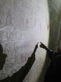 Egyptský dělník si prohlíží hieroglyfy v hrobce jižně od Káhiry