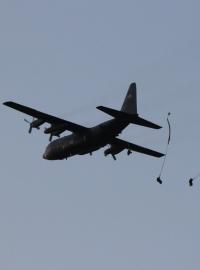 Parašutisté vyskakují z amerického dopravního letadla C-130 Herkules.