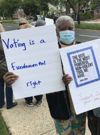 Protestující s nápisy „hlasování je základní právo“ a „toto je nejmocnější nenásilný nástroj, který máme“.