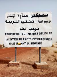 Cedule na cestě do Timbuktu napsaná islamistickými povstalci z roku 2013. Stojí na ní: Timbuktu, minaret islámu a brána k uplatňování zákona šaría vás vítá.