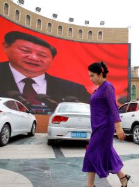 Ujgurka prochází kolem obří plochy s podobiznou čínského prezidenta Si Ťin-pchinga na hlavním náměstí ve městě Kašgar voblasti Sin-ťiang.