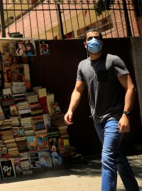 Muž s rouškou prochází kolem pouličního knihkupectví v centru Káhiry.