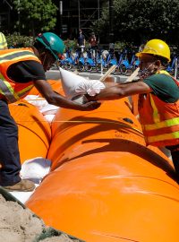 Pracovníci v New Yorku skládají pytle s pískem na protipovodňovou hráz.