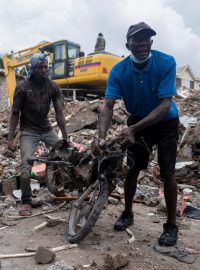 Muži odklízejí odpad, který zbyl po zemětřesení v haitském Les Cayes