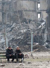 Obyvatelé obklíčeného Mariupolu před vybombardovanými budovami