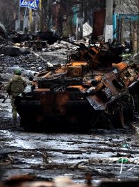 Voják pózuje u ruského zničeného tanku a obrněných vozidel ve městě Buča poblíž Kyjeva