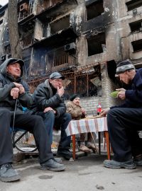 Obyvatelé Mariupolu sedí před zničenou budovou