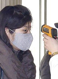 Dobrovolnice měří teplotu ženě před testem na koronavirus v Severní Korei
