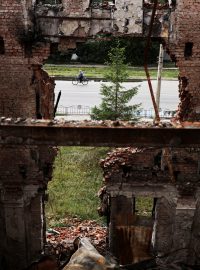 Muž jede na kole před zničenou školou v Charkově