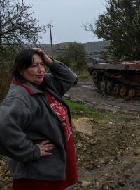 Žena postává vedle zničeného obrněného vozidla v osvobozené vesnici Kamjanka v Charkovské oblasti
