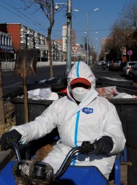 Pracovník úklidu v ochranném obleku v ulicích Pekingu, 4. prosince 2022