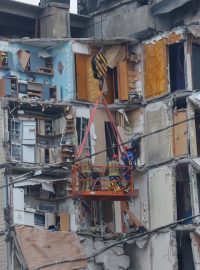 Záchranáři pracují na místě, kde byl při zásahu ruskou raketou těžce poškozen bytový dům