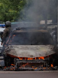 Příslušníci speciálních policejních jednotek stojí u hořícího auta po střetech mezi kosovskou policií a protestujícími etnickými Srby